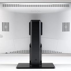Ansicht der R&uuml;ckseite eines Monitors mit schwarzem Standfu&szlig; und wei&szlig;en L&uuml;ftungsgittern, mit der Marke &bdquo;BARCO&ldquo; oben.